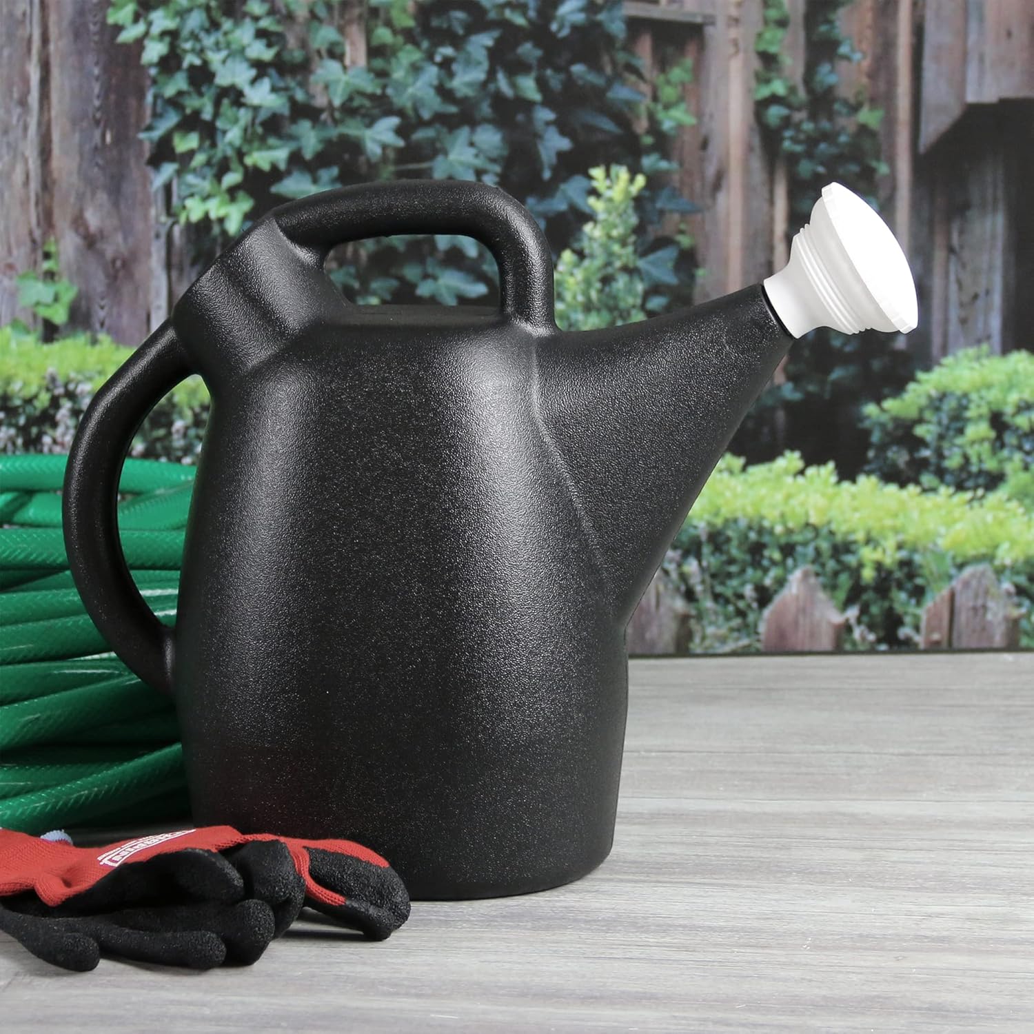 Metal watering can and adjustable hose nozzle on patio table.